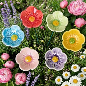 May include: A collection of six ceramic flower garden stakes in red, light green, blue, yellow, light pink, and purple. Each flower features a glossy finish, five rounded petals, and a raised yellow center, all mounted on thin green metal stems.