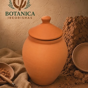 May include: A terracotta clay jar with a matching lid, featuring a rounded body and a smooth finish. The logo for BOTANICA IREORISHAS is visible in the upper left corner, featuring a horseshoe, a nail, and leafy branches in dark green.