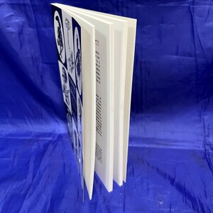 May include: A book with a white cover and pages, featuring black and white illustrations. The cover displays several images in a grid pattern. The book is open, revealing the text on the pages.
