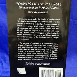 May include: A book titled "POWERS OF THE ORISHAS Santeria and the Worship of Saints" by Migene Gonzalez-Wippler. The book's cover is dark with white text. The text describes the history of Santeria and its syncretic relationship with Catholicism.