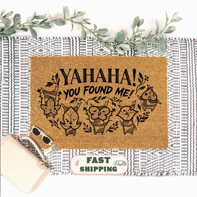 K&ouml;nnte beinhalten: Rechteckige Fu&szlig;matte aus Naturkokosfaser. Der Schriftzug "YAHAHA! YOU FOUND ME!" ist in Schwarz aufgedruckt, zusammen mit einer Grafik von f&uuml;nf Cartoon-Figuren. Die Matte liegt auf einem schwarz-wei&szlig; gemusterten Teppich, mit Gr&uuml;nzeug.