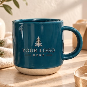 May include: A deep teal ceramic mug with a smooth, glossy finish and a light grey, speckled base. The front of the mug features a gold-coloured line art graphic of a pine tree above the centred text "YOUR LOGO HERE" in a clean font.