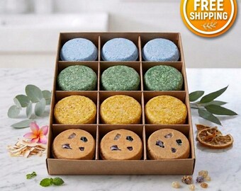 May include: A cardboard box containing twelve round shampoo bars arranged in four rows. The top row features three light blue bars, the second row has three green bars, the third row contains three yellow bars, and the bottom row has three tan bars with embedded dark stones.