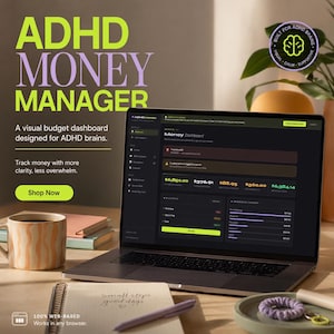 May include: A laptop displays the "ADHD Money Manager" dashboard, with the text "ADHD MONEY MANAGER" in large letters. The screen shows financial data. A coffee mug, notebook, and pen are on the desk.