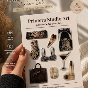 May include: Aesthetic sticker set with a 3D glossy finish. The set includes various designs such as a leopard print, a handbag, a cocktail, and a lipstick. The text on the card reads "Printera Studio Art" and "Add a touch of luxury to anything!"