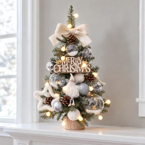 May include: A tabletop artificial Christmas tree featuring a wooden base, a large cream-colored fabric bow at the top, and a wooden sign reading Merry Christmas. It is decorated with clear glass ornaments, pinecones, white stars, and a small gnome.