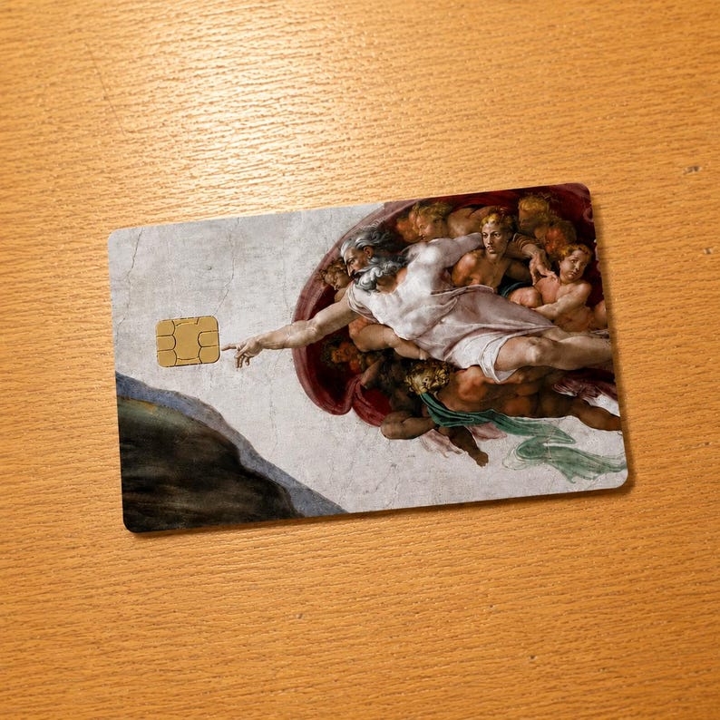 May include: A rectangular credit card featuring a detail from Michelangelo's "The Creation of Adam" fresco. The card has a gold-colored EMV chip on the left side and the artwork covers the rest of the card.