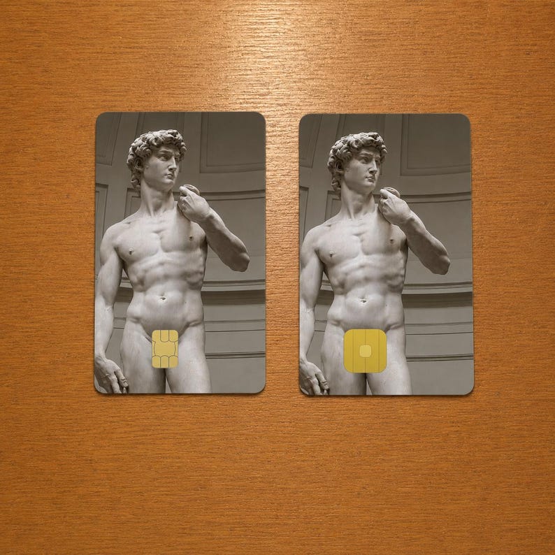 Op de afbeelding: Twee rechthoekige kaarten met een grijswaardenafbeelding van Michelangelo's David-standbeeld. Elke kaart heeft een gele vierkant die de geslachtsdelen van het standbeeld bedekt. De kaarten liggen op een houten oppervlak.