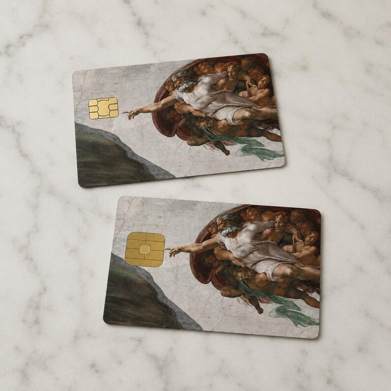 May include: Two rectangular cards featuring a section of Michelangelo's "The Creation of Adam" painting. The cards have a gold-colored chip on the left side. The artwork depicts two figures with outstretched arms, nearly touching.