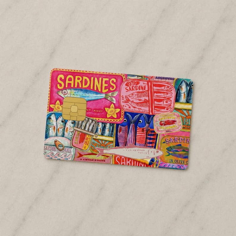 May include: A credit card design featuring a vibrant illustration of sardines. The card showcases various sardine tins and fish, with the word "SARDINES" prominently displayed in pink. The design includes a gold-colored chip.