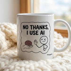 Könnte beinhalten: Ein weißer Keramikbecher mit einer schwarzen Strichzeichnung einer Strichmännchen-Figur, die eine Hand mit einem Gehirn abwehrt. Der Text darüber lautet NO THANKS, I USE AI, und das Wort Muggish steht klein unten rechts.