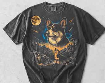 May include: Dark gray t-shirt featuring a detailed illustration of a corgi dog under a full moon and starry night sky. The design includes a smaller corgi silhouette and mountain landscape.