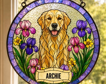 May include: A circular stained glass suncatcher featuring a golden retriever dog at the center, surrounded by purple and pink iris flowers and small yellow blossoms. A banner at the bottom displays the name ARCHIE in black capital letters.