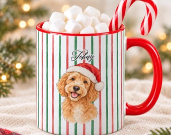 May include: A white ceramic mug with vertical red and green stripes, featuring a hand-drawn illustration of a golden-colored dog wearing a red Santa hat. The name Johny is printed above the dog. The mug is filled with white marshmallows and a candy cane.