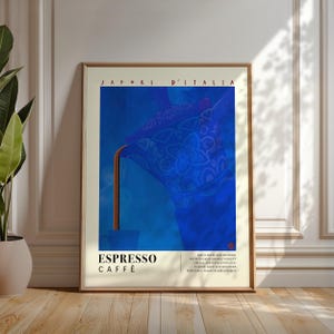 May include: Framed art print featuring a blue coffee pot pouring espresso into a cup. The poster has the text "SAPORI D'ITALIA" at the top and "ESPRESSO CAFFÈ" at the bottom. The artwork is displayed on a wooden floor.