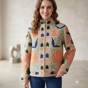 May include: A beige herringbone jacket with a high collar and a full-length front zip. The jacket features colourful embroidered floral and leaf patterns in shades of orange, blue, and green across the front and sleeves.