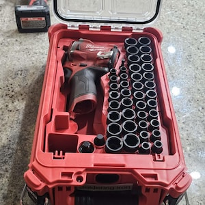 May include: A red Milwaukee power tool set with a clear lid, featuring a drill, sockets, and accessories. The set is neatly organized within a red case, with a second power tool visible in the background.