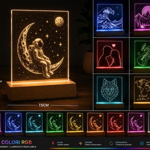 Può includere: Lampada LED decorativa con un astronauta seduto sulla luna su sfondo stellato. La lampada, alta 15 cm, ha una base in legno e un pannello in acrilico trasparente. Offre 16 colori RGB.