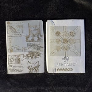 May include: Two white notebooks. The left notebook features handwritten notes and sketches of architectural structures and figures. The right notebook displays a geometric grid of circular patterns, the word PENTALIC, and six hexagonal icons.