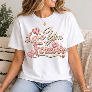 May include: White t-shirt with the text "Love You Forever" in gold and pink script, featuring heart accents. The design has a glittery effect, ideal for Valentine's Day or expressing affection. A casual and romantic apparel item.