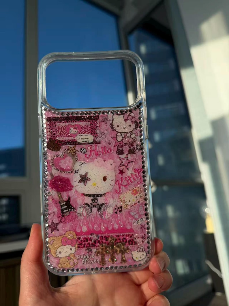 May include: Clear phone case with a pink interior featuring Hello Kitty graphics, stars, and the word "Kitty." The case is embellished with rhinestones around the edges and includes the text "Bubble Planet."