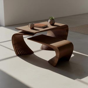 Può includere: Un tavolino da caffè in legno marrone scuro con un design curvo e a più livelli, caratterizzato da una struttura a doghe. Sulla superficie superiore si trovano una tazza in ceramica, un libro rettangolare chiuso e un piccolo vaso geometrico con una succulenta.