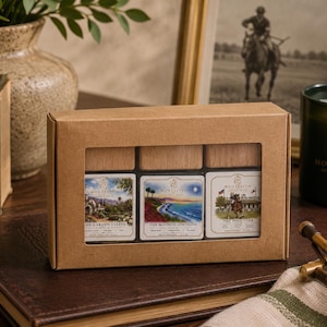 Könnte beinhalten: Eine rechteckige Geschenkbox aus braunem Karton mit einem Sichtfenster, das drei Glasflaschen mit Holzverschlüssen zeigt. Jede Flasche hat ein Etikett mit Illustrationen namens The Garden Estate, The Moonlit Coastline und The Polo Club.