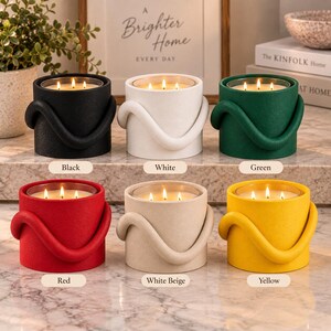 Puede incluir: Seis velas cil&iacute;ndricas en negro, blanco, verde, rojo, beige y amarillo. Cada vela presenta un exterior texturizado con un lazo decorativo grueso y curvo alrededor del lateral y tres mechas encendidas dentro de un inserto de vidrio.