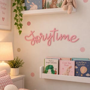 May include: A pink script wall sign reading Storytime mounted between two white floating shelves. The shelves hold children's books including Good Night, Little Bunny, Little Bear's Big Adventure, The Very Hungry Caterpillar, and Oh, the Places You'll Go!, plus a plush bunny toy.