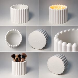 May include: A white cylindrical container with a vertical ribbed exterior and a scalloped top edge. The base features the embossed cursive text "claire". It is shown empty, as a candle with three lit wicks, and as a holder for makeup brushes.
