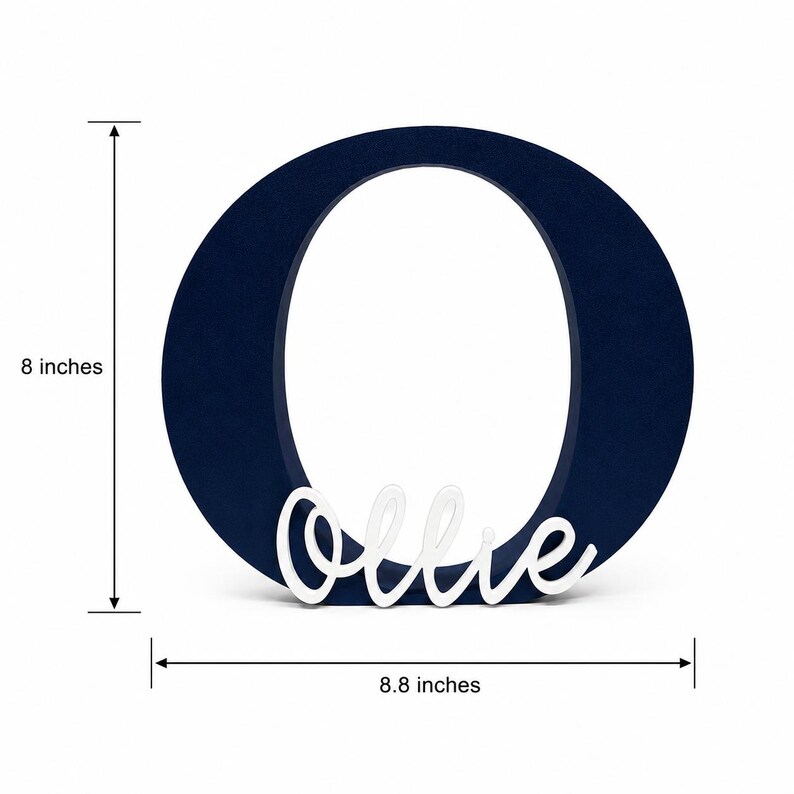 Puede incluir: Una letra "O" de madera azul marino con el nombre "Ollie" en escritura blanca. La letra mide 20.3 cm de alto y 22.4 cm de ancho. Este art&iacute;culo decorativo es adecuado para la decoraci&oacute;n de guarder&iacute;as o regalos personalizados.