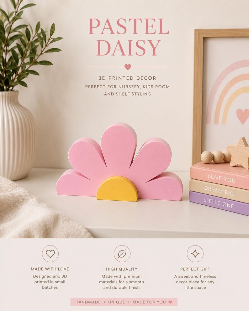 K&ouml;nnte beinhalten: Ein pastellrosa, g&auml;nsebl&uuml;mchenf&ouml;rmiges 3D-gedrucktes Dekorst&uuml;ck mit gelber Mitte. Das Bild zeigt auch eine Vase mit Gr&uuml;n, einen gerahmten Regenbogen-Druck und gestapelte B&uuml;cher mit den S&auml;tzen "I LOVE YOU", "DREAM BIG" und "LITTLE ONE". Der Text lautet "PASTEL DAISY".