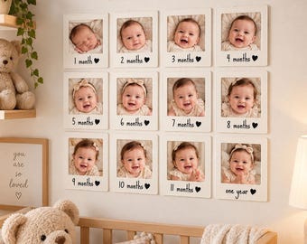 May include: A wall-mounted photo display featuring twelve square white frames arranged in a grid, each containing a baby portrait labeled from 1 month to one year. Above the frames, the wooden text reads our little one with a heart symbol.