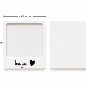 May include: Two white square frames, one with a hollow center and the text "love you" with a black heart icon. The frame measures 4.00 inches in width and 4.80 inches in height. The second frame is a solid white square of the same dimensions.