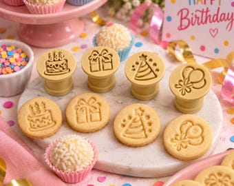 Puede incluir: Un juego de cuatro sellos para galletas circulares de color beige con diseños en relieve de un pastel de cumpleaños, una caja de regalo, un gorro de fiesta y globos, junto a galletas estampadas, dulces con virutas y una tarjeta.
