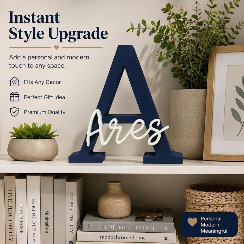 May include: A navy blue wooden letter "A" with the name "Ares" in white script. The decorative piece is displayed on a white shelf with books, a small plant, and other home decor items. The text "Instant Style Upgrade" is visible.