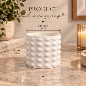 May include: A white cylindrical planter with a textured, dimpled surface. Text on the image indicates product dimensions of 4.9 inches in diameter and 3.7 inches in height. The planter is shown with the text PRODUCT dimensions and TIMELESS DECOR.