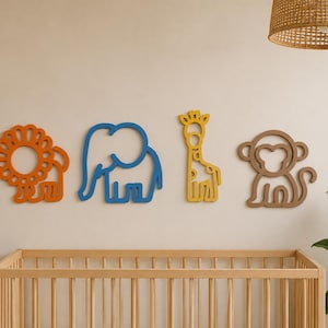 May include: Four colorful wooden animal cutouts: a lion, elephant, giraffe, and monkey. The lion is orange, the elephant is blue, the giraffe is yellow, and the monkey is brown. They are mounted on a light-colored wall above a wooden crib.