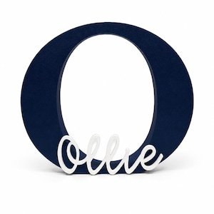 Puede incluir: Una letra "O" de madera azul marino con el nombre "Ollie" en escritura blanca. La letra es gruesa y se mantiene de pie, perfecta para la decoraci&oacute;n de la guarder&iacute;a o regalos personalizados.