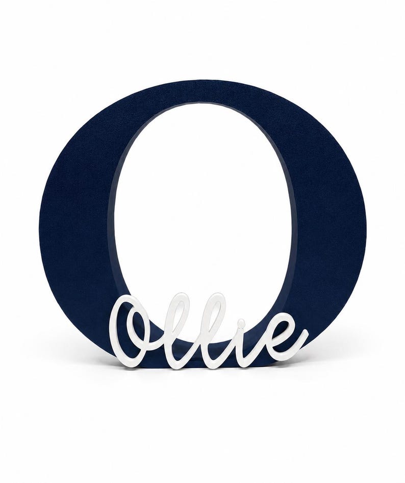 Puede incluir: Una letra "O" de madera azul marino con el nombre "Ollie" en escritura blanca. La letra es gruesa y se mantiene de pie, perfecta para la decoraci&oacute;n de la guarder&iacute;a o regalos personalizados.