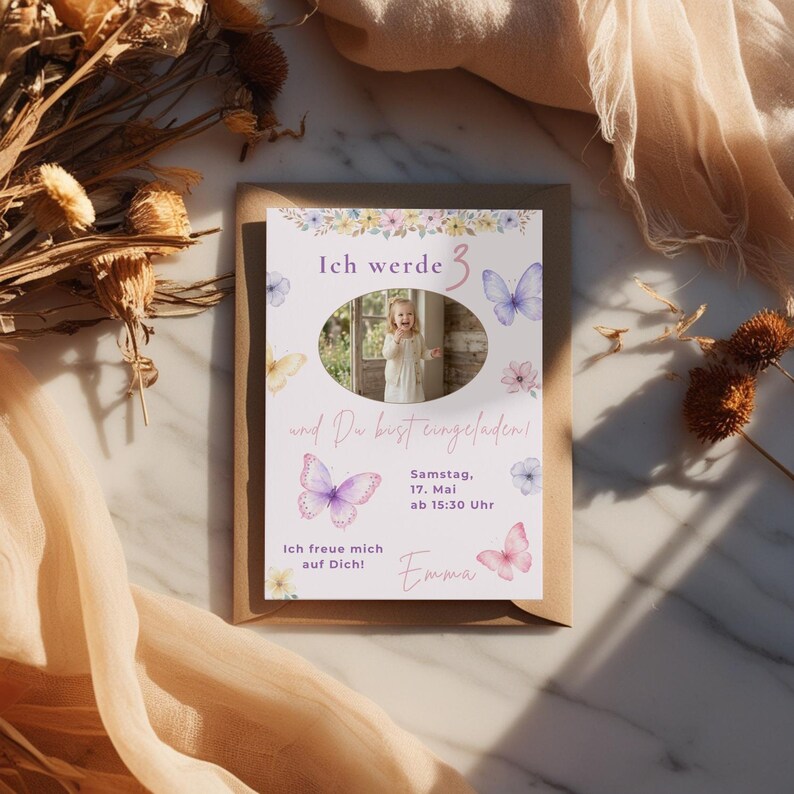 May include: A rectangular birthday invitation card featuring watercolor butterflies and flowers, with a central oval photo of a child. The text reads: Ich werde 3, und Du bist eingeladen!, Samstag, 17. Mai ab 15:30 Uhr, Ich freue mich auf Dich!, and Emma.