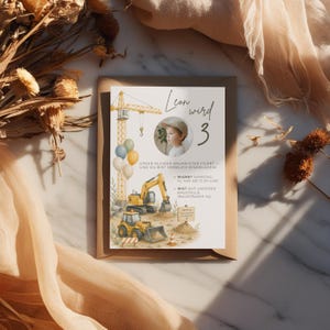 May include: A birthday invitation featuring a watercolor illustration of construction vehicles, a crane, and balloons. The invitation includes the text "Leon wird 3" and event details. The invitation is set on a brown envelope.