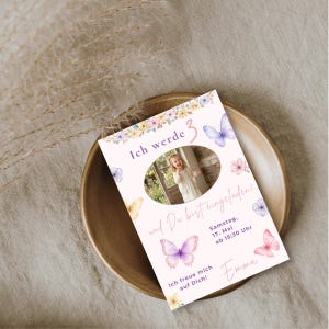 May include: A rectangular birthday invitation card featuring a central oval photo of a child, decorated with watercolor illustrations of purple, pink, and yellow butterflies and flowers. Text includes Ich werde 3, und Du bist eingeladen!, Samstag, 17. Mai ab 15:30 Uhr, Ich freue mich auf Dich! and the name Emma.