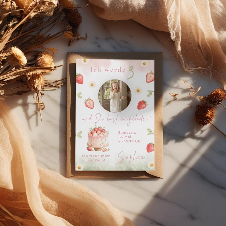 May include: A rectangular birthday invitation card featuring a circular photo of a child, watercolor strawberries, daisies, and a cake illustration. The text reads: Ich werde 3, und Du bist eingeladen!, Samstag, 17. Mai ab 15:30 Uhr, Sophia, Ich freue mich auf Dich!
