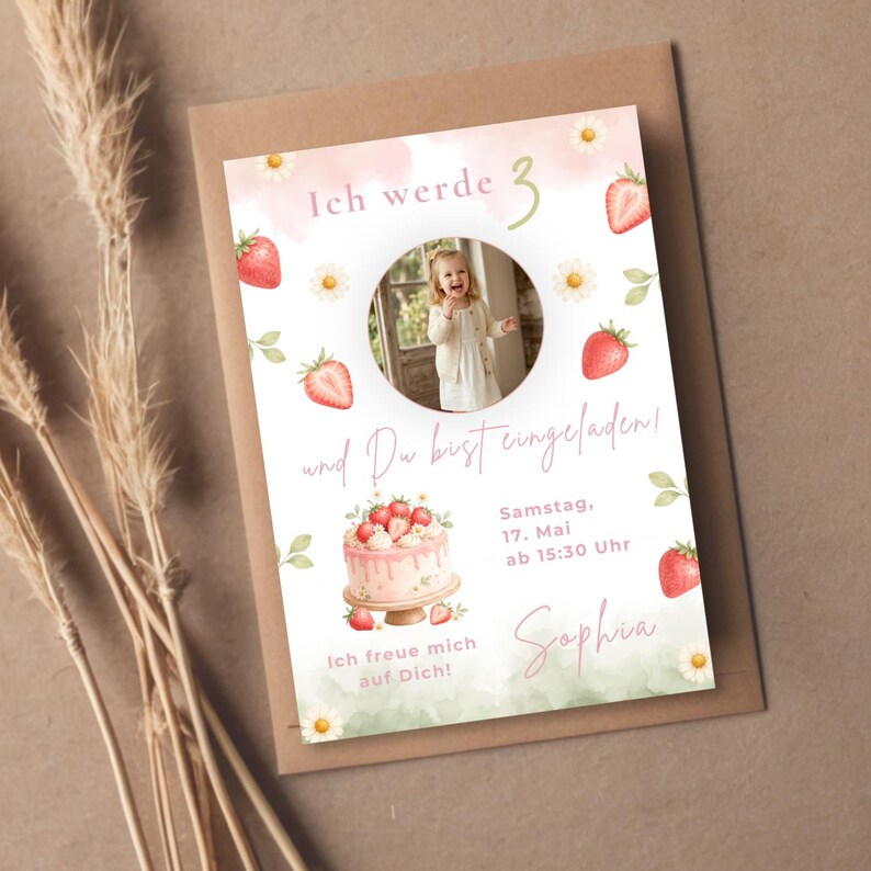 May include: A rectangular birthday invitation card featuring a circular photo of a child, watercolor strawberries, and daisies. The text reads Ich werde 3 und Du bist eingeladen! Samstag, 17. Mai ab 15:30 Uhr, Sophia, Ich freue mich auf Dich! with a cake illustration.