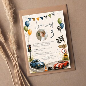 Pu&ograve; includere: Un biglietto d'invito per compleanno a tema corse con una foto circolare di un bambino, il testo Leon wird 3, palloncini colorati, bandiere a scacchi, un semaforo, un'auto blu, un'auto rossa e festoni su uno sfondo color crema.
