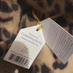 May include: A soft toy with a tag saying "Cobblehop Bunny, Please look after me." The tag also includes the text "For the joy of it. jellycat.com" and a barcode. The toy has a brown and tan leopard print design.