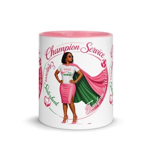 Puede incluir: Una taza de cerámica blanca con interior rosa que presenta un gráfico de una persona con capa de superhéroe, vistiendo una camiseta blanca con el texto Service to all Mankind y una falda rosa. El diseño incluye el texto Champion Service y Empower Sisterhood.