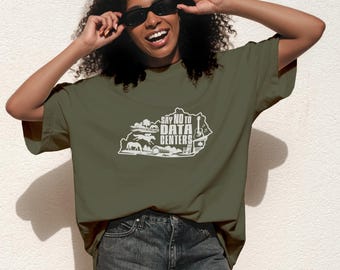 Op de afbeelding: Een olijfgroen T-shirt met korte mouwen en een witte afbeelding van de staat Kentucky. De afbeelding bevat silhouetten van paarden, een schuur en een gitaar, met de tekst "SAY NO TO DATA CENTERS" gedrukt in het midden van de omtrek.