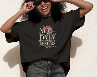 Op de afbeelding: Een zwart t-shirt met korte mouwen en een grafische print van roze rozen en groene bladeren in een wit rechthoekig kader. De tekst NO DATA CENTERS is in witte hoofdletters over het bloemmotief op de borst gedrukt.